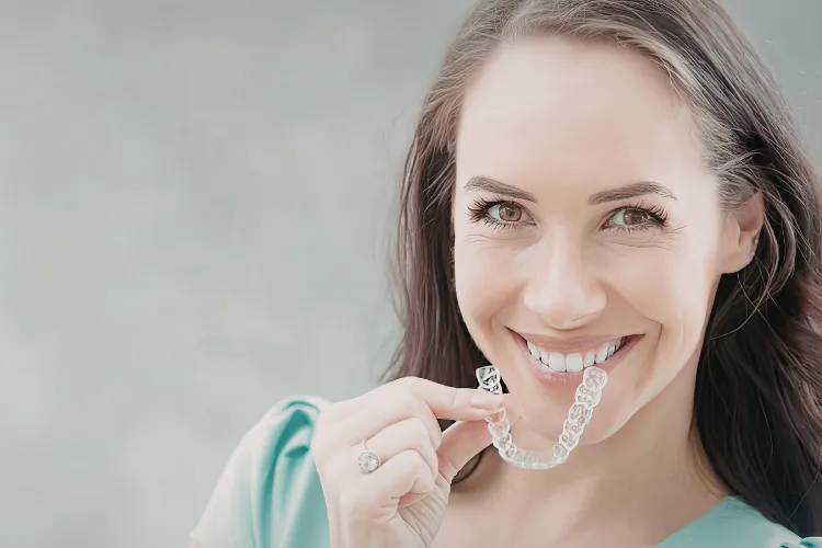 Woman displaying clear aligners before treatment, highlighting the benefits of starting clear aligner orthodontic treatment during the summer.