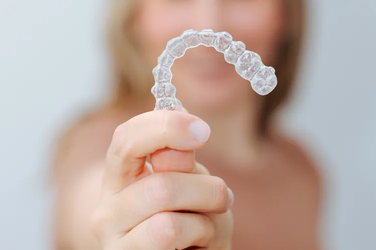 Person holding a clear aligner tray, illustrating convenient orthodontic treatment and travel-friendly clear aligner care during summer vacations.